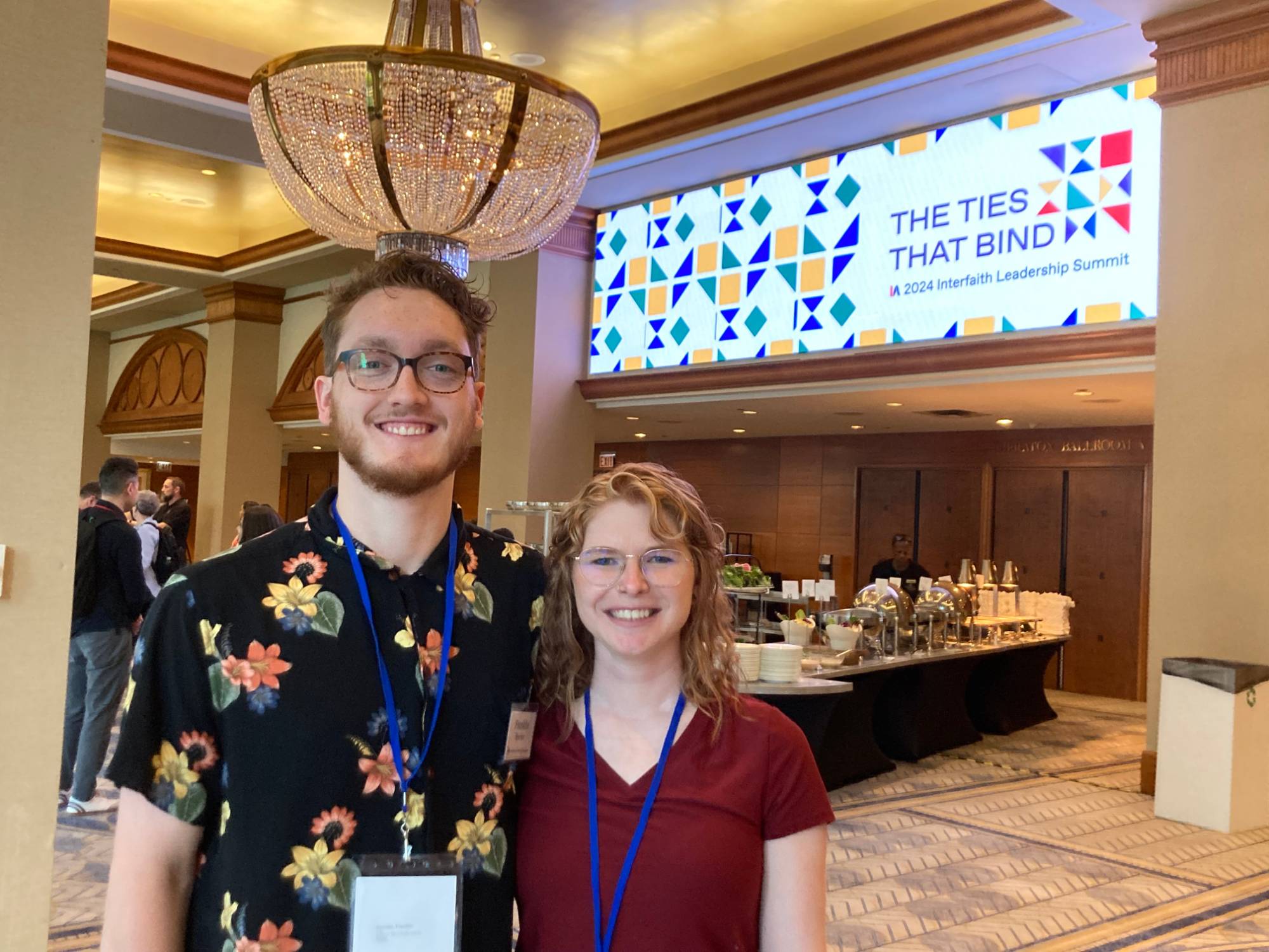 Franklin and Rachel members of the Interfaith Student Council standing in front of a sign that says The Ties That Bind